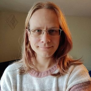 A self-portrait of the author: a smiling white person with long, blonde hair and a fluffy jumper.