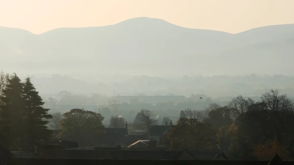 A view southwards from the west of Edinburgh shows the city shrouded in the haar, with warm morning light breaking through.